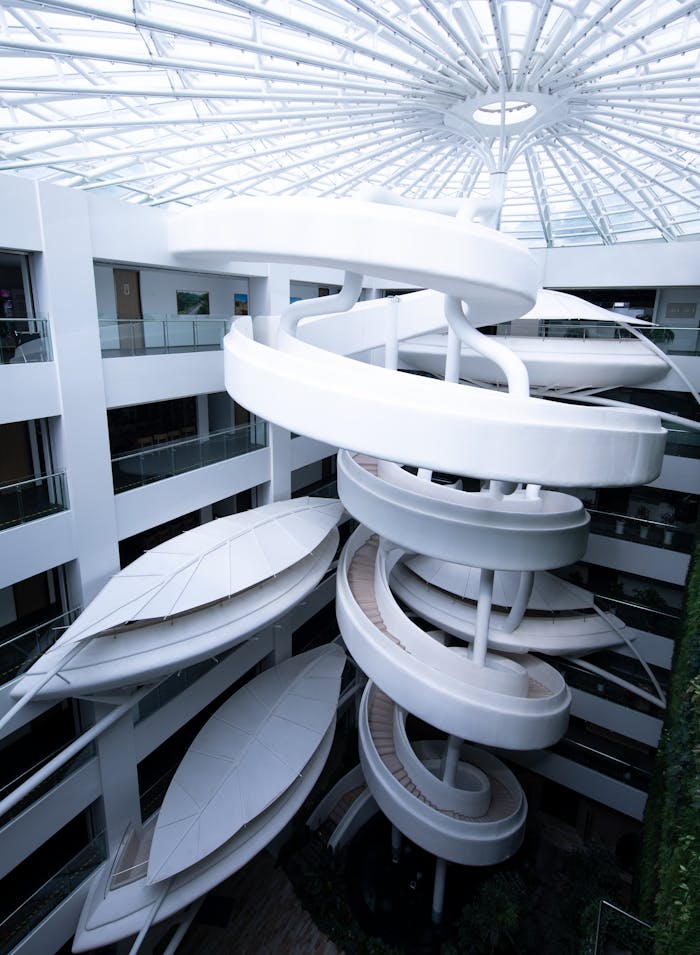Elegant spiral staircase in a modern atrium with a skylight architectural design.