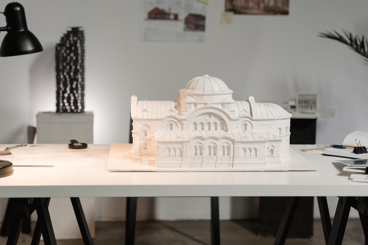 Intricate architectural model displayed on a designer's worktable in an office setting.