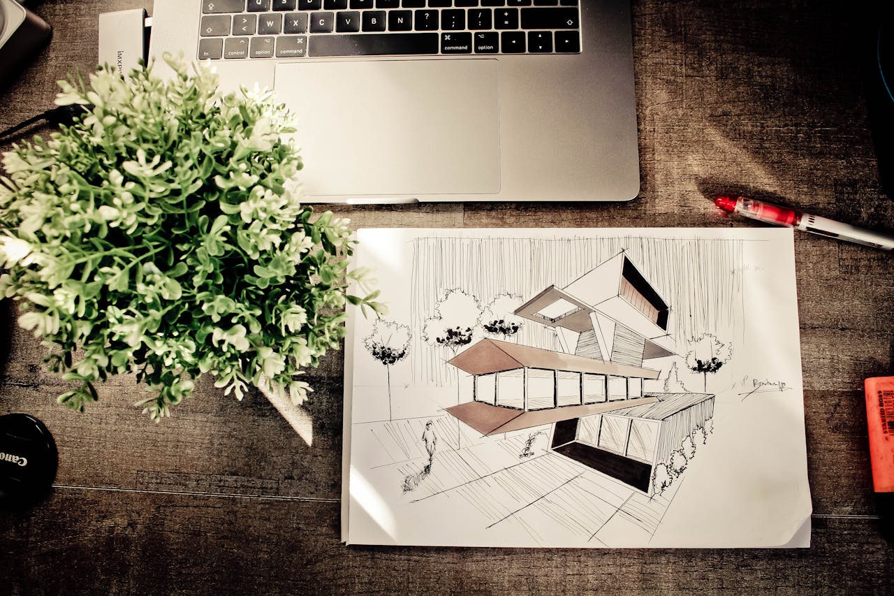 A detailed architectural design sketch on an office desk with a laptop and plant, fostering creativity.